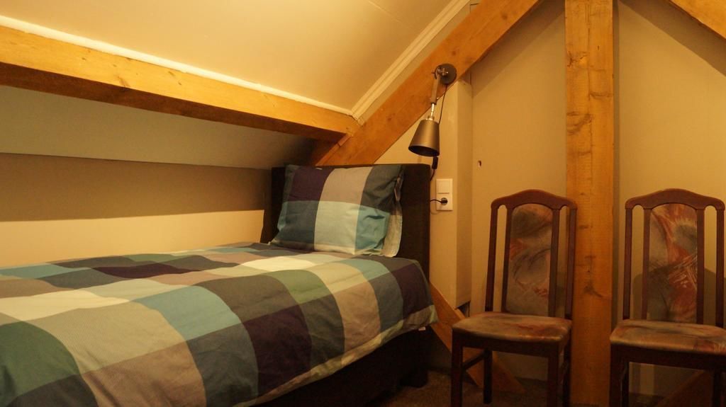 Un dormitorio con una cama, una silla y una lámpara.
