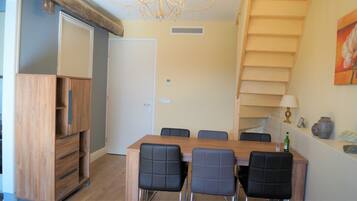 A dining area with a wooden table and six chairs, a wooden cabinet, and a staircase with a railing.