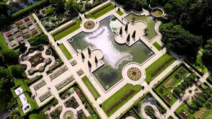 Vue aérienne d’un jardin à la française, caractérisé par ses motifs géométriques, ses fontaines et ses pelouses parfaitement entretenues.