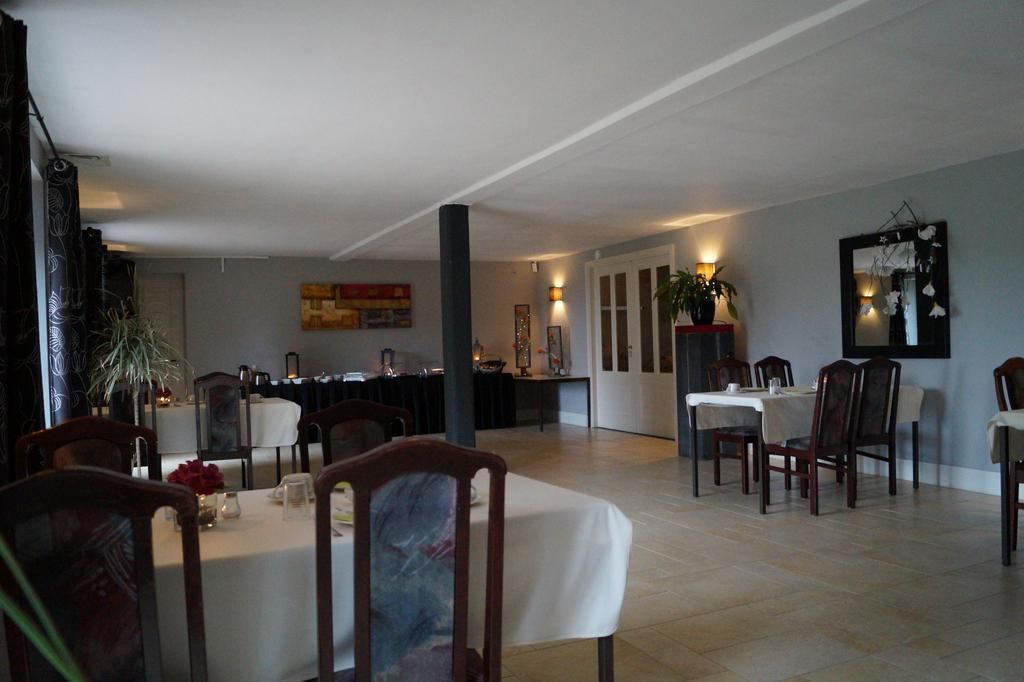 A dining area with tables and chairs, a large mirror, and a plant.