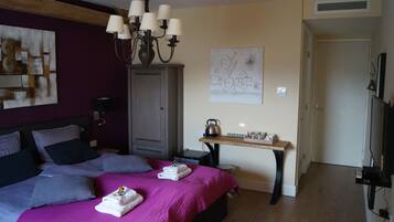 Een hotelkamer met een bed, een bureau, een waterkoker en een schilderij aan de muur.