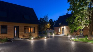 Un immeuble résidentiel moderne doté d’une allée pavée, d’une façade en bois et d’un éclairage extérieur.