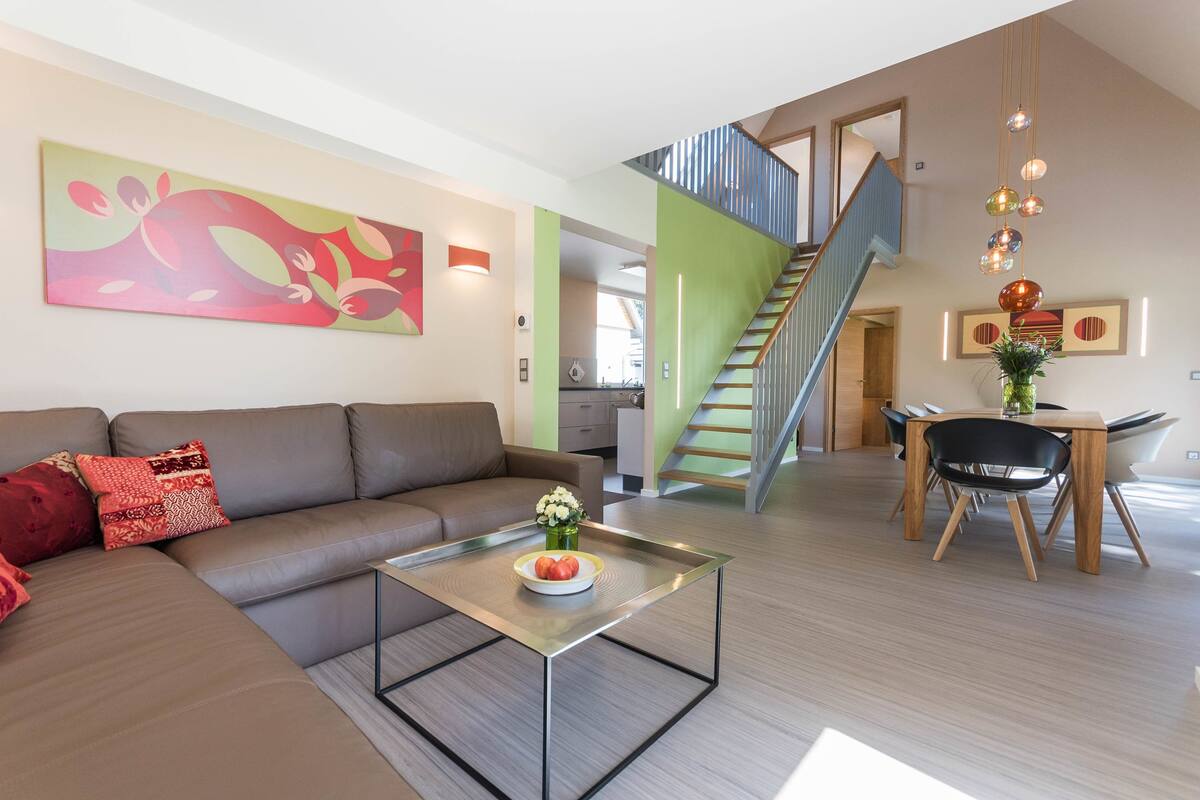 A modern living room with a sofa, coffee table, and a staircase leading to an upper level.