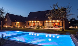 A modern house with a swimming pool, outdoor seating, and a garage.