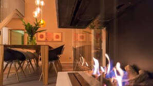 Un salon moderne avec une cheminée, un coin repas comprenant des chaises et une table, et un escalier menant à un niveau supérieur.