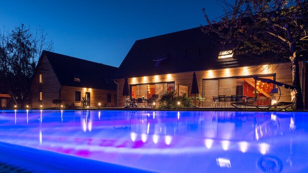 Un bâtiment moderne doté d’une piscine, photographié au crépuscule.