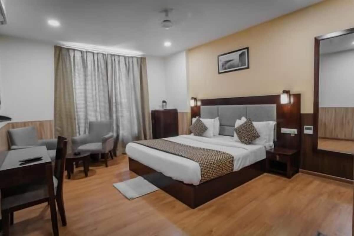 Habitació d'hotel amb un llit gran, una taula de treball, una cadira, un armari i un mirall.