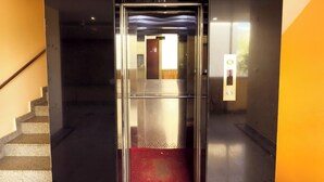 An elevator with a red carpet, a staircase to the left, and a wall with a light switch. - Royal Palm - Hotel Near Udaipur Railway Station (Udaipur)