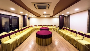 A conference room with a long table and chairs, wooden floors, and a ceiling with recessed lighting. - Royal Palm - Hotel Near Udaipur Railway Station (Udaipur)