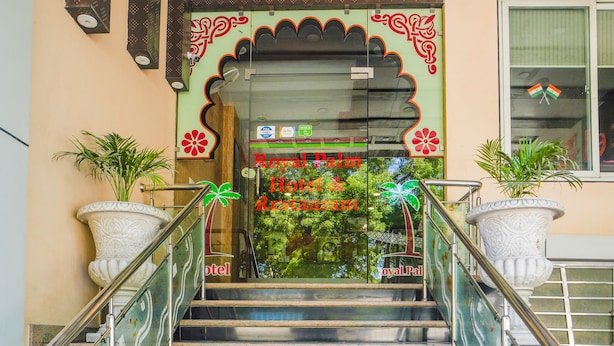 A staircase leading to a hotel entrance with a decorative archway and potted plants on either side. - Royal Palm - Hotel Near Udaipur Railway Station (Udaipur)