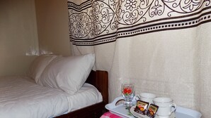 Una cama bien hecha con ropa de cama blanca, un cabecero de madera y una cortina decorativa con estampado en blanco y negro.