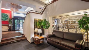 A modern interior with a staircase, a leather sofa, a coffee table, and a bar area with various bottles. - Hotel Oxford (Rome)