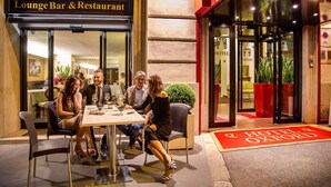 A group of people dining at a lounge bar and restaurant with a visible entrance to the Hotel Oxford. - Hotel Oxford (Rome)