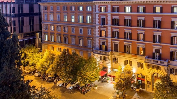 A multi-story hotel with a classic architectural style, featuring a central courtyard with trees and a small fountain. - Hotel Oxford (Rome)
