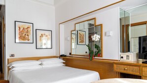 A hotel room with a large bed, a bedside table with a radio, a mirror, and two framed artworks on the wall. - Hotel Oxford (Rome)