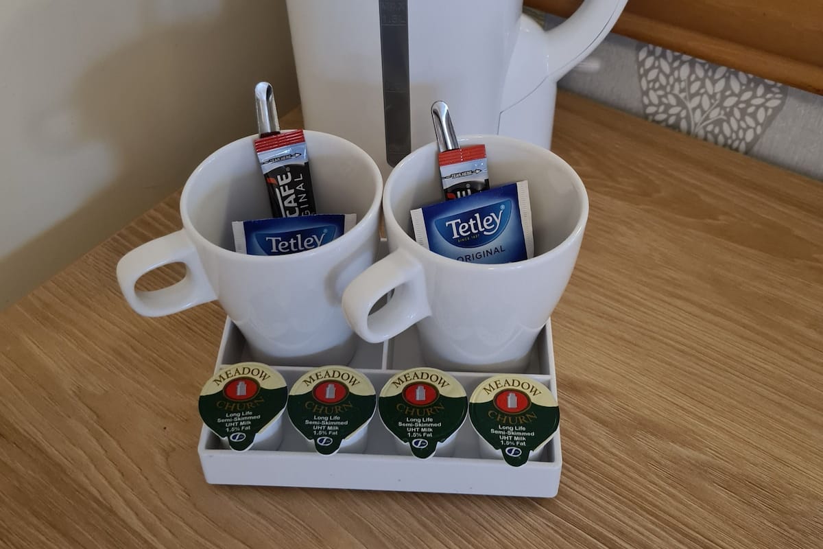 Angolo cottura con una moka, due tazze con tè Tetley e un vassoio con brick di latte Meadow Churn.
