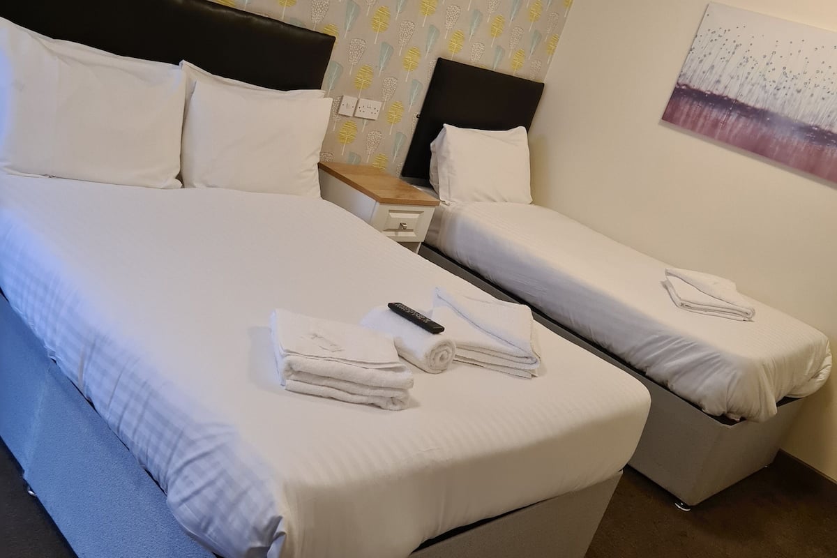 Una camera d'albergo con due letti, un comodino e un quadro appeso al muro.