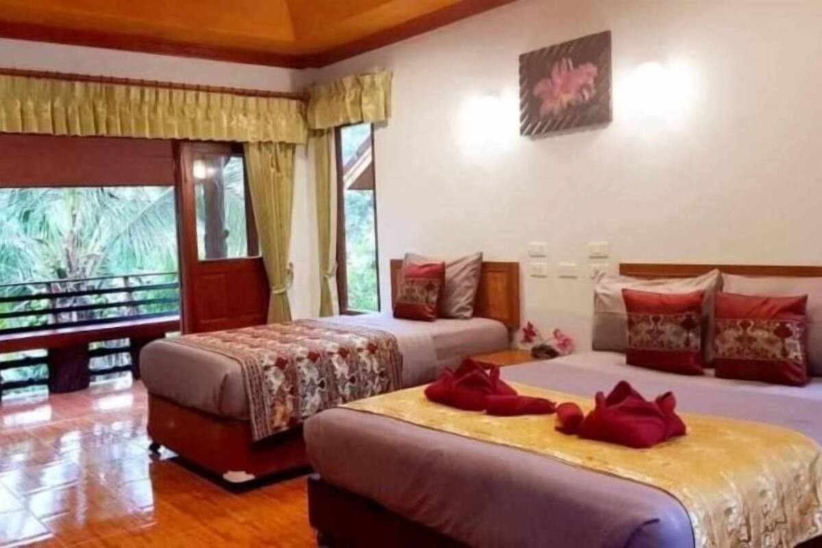 Une chambre avec deux lits, un banc et une fenêtre avec des rideaux.