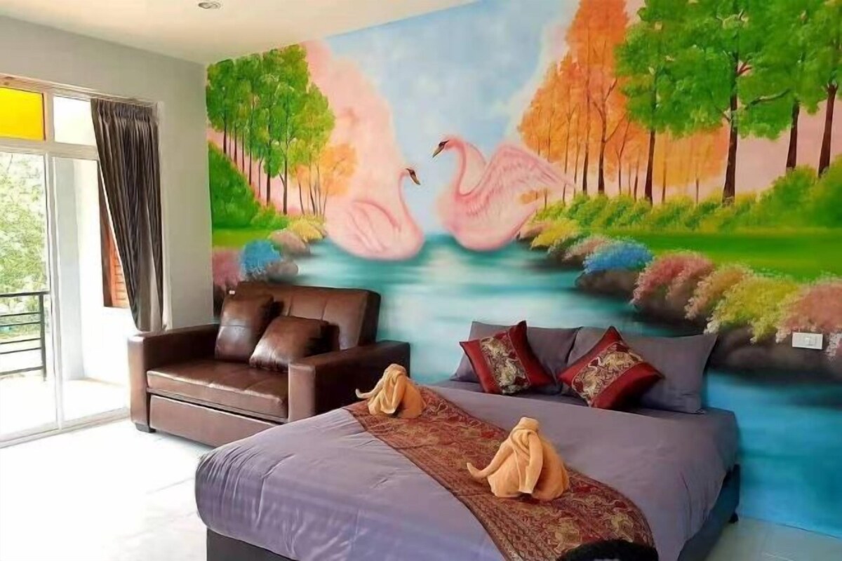 Een slaapkamer met een bed, een slaapbank en een muurschildering van flamingo's en bomen.