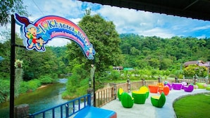 A sign for Khao Soi Khlong Ratchaburi with colorful chairs and a river view. - Khaosok Rainforest Resort (Phanom)