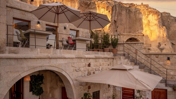 A stone building with outdoor seating and a view of a mountain. - Serinn House (Urgup)