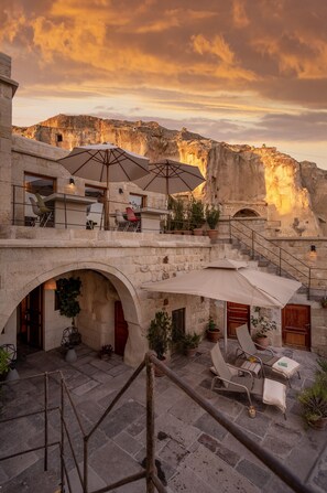 A stone building with outdoor seating and a view of a mountain. - Serinn House (Urgup)