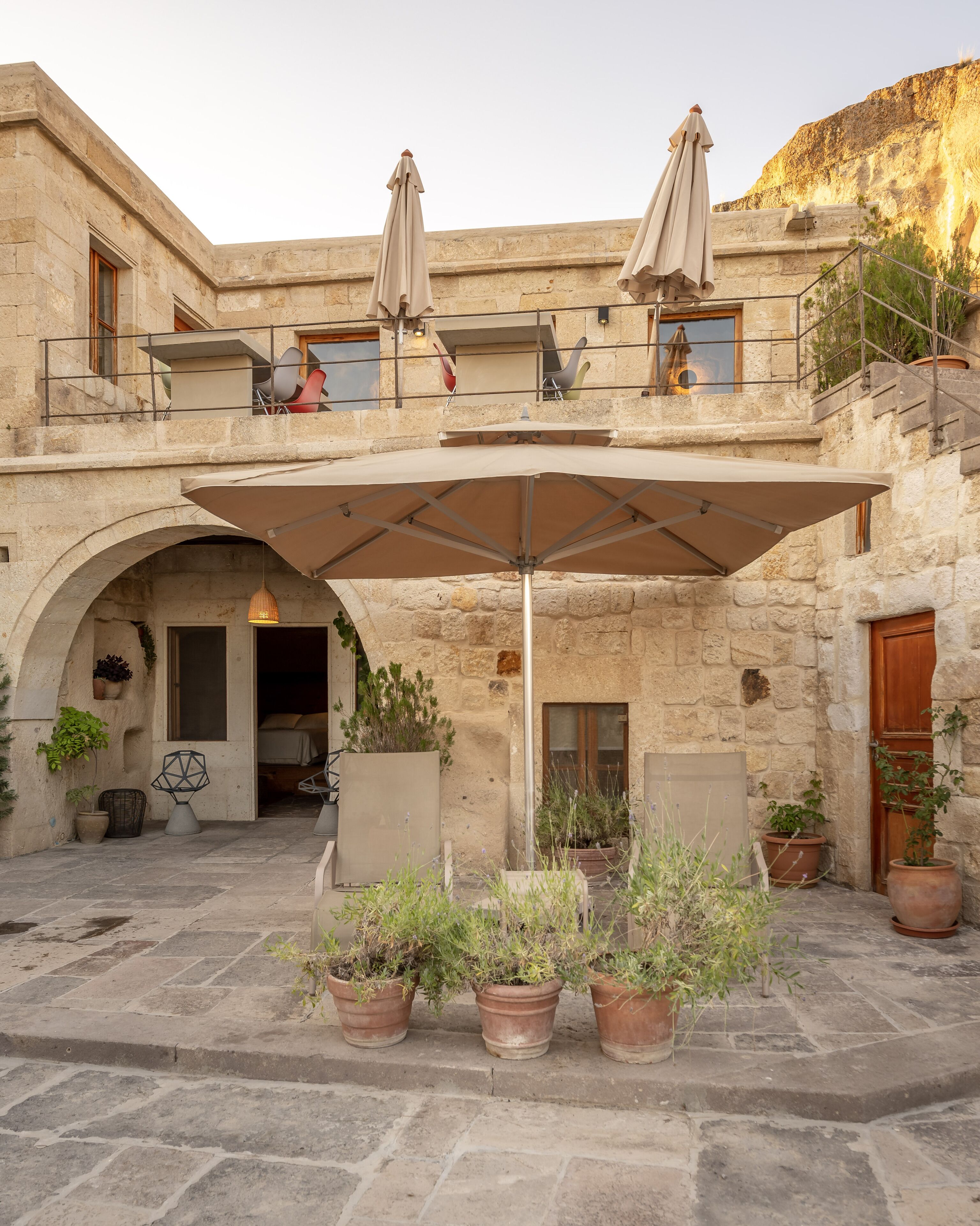 A stone building with a covered patio, outdoor seating, and potted plants.