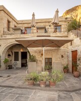 A stone building with a covered patio, outdoor seating, and potted plants.