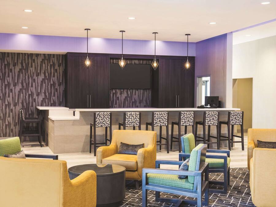 A modern lounge area with a bar, seating arrangements, and a television screen.