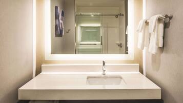 Un baño con un espejo grande, un lavamanos y un perchero para toallas.