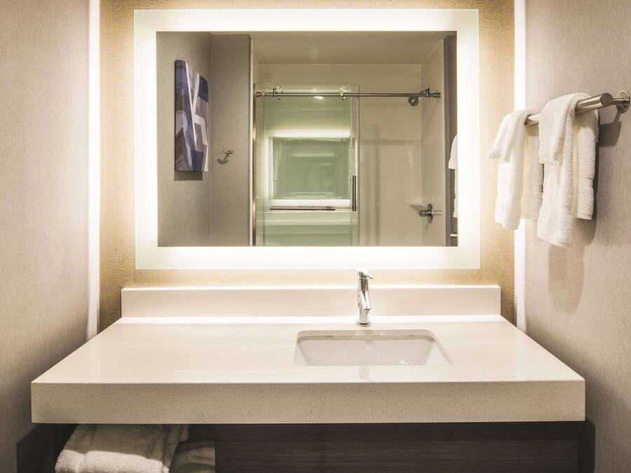 Un baño con un espejo grande, un lavamanos y un perchero para toallas.