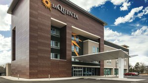 Un hôtel La Quinta au design moderne, avec un logo solaire bien visible, de grandes fenêtres et un espace d’entrée abrité.