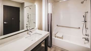 A modern bathroom with a white sink, mirror, and a walk-in shower with a glass door.
