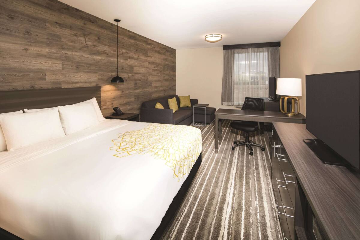 Une chambre d’hôtel avec un grand lit, un bureau, une chaise, une lampe et un téléviseur.