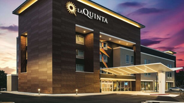 Un hotel moderno con un llamativo letrero de 'La Quinta', un acceso cubierto y una fachada bien iluminada.