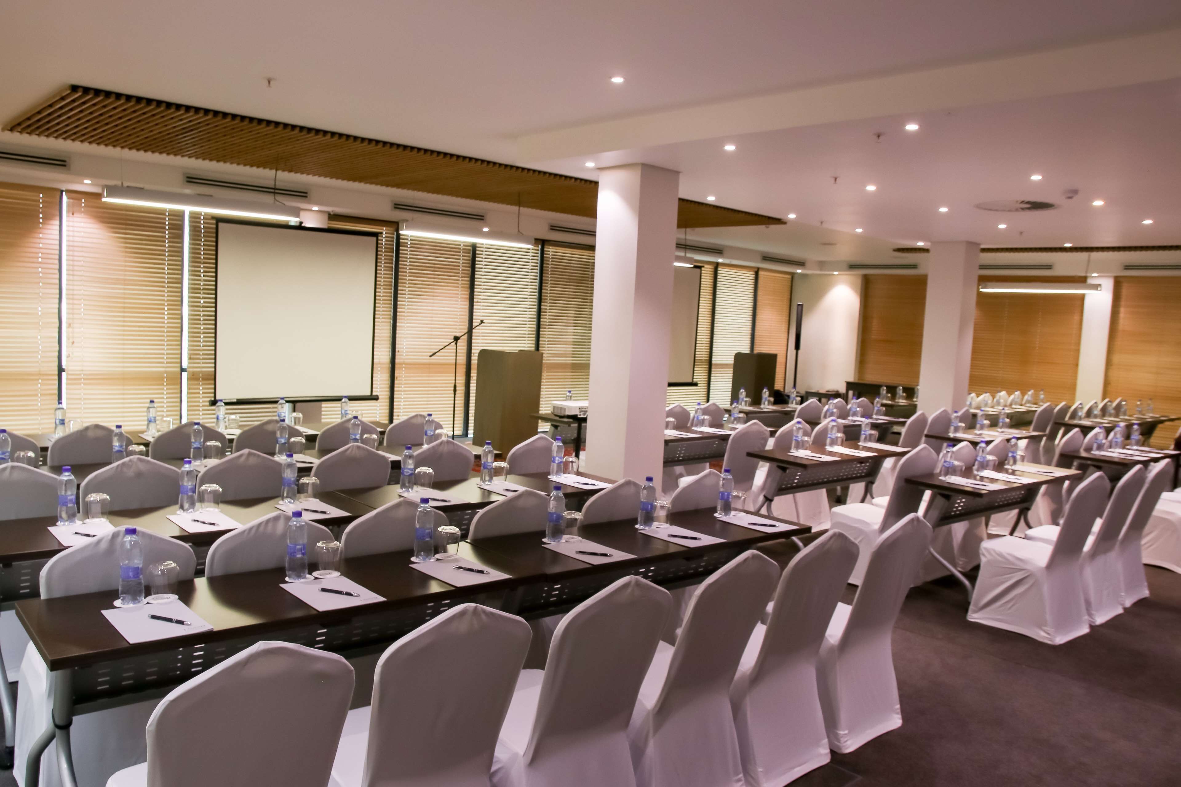 A conference room with rows of tables, chairs, and water bottles.