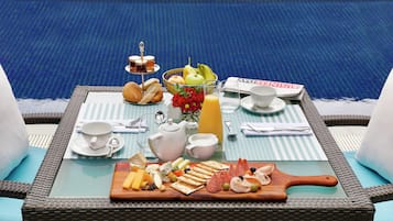 A breakfast table with a variety of food items, a fruit bowl, a teapot, and a newspaper.