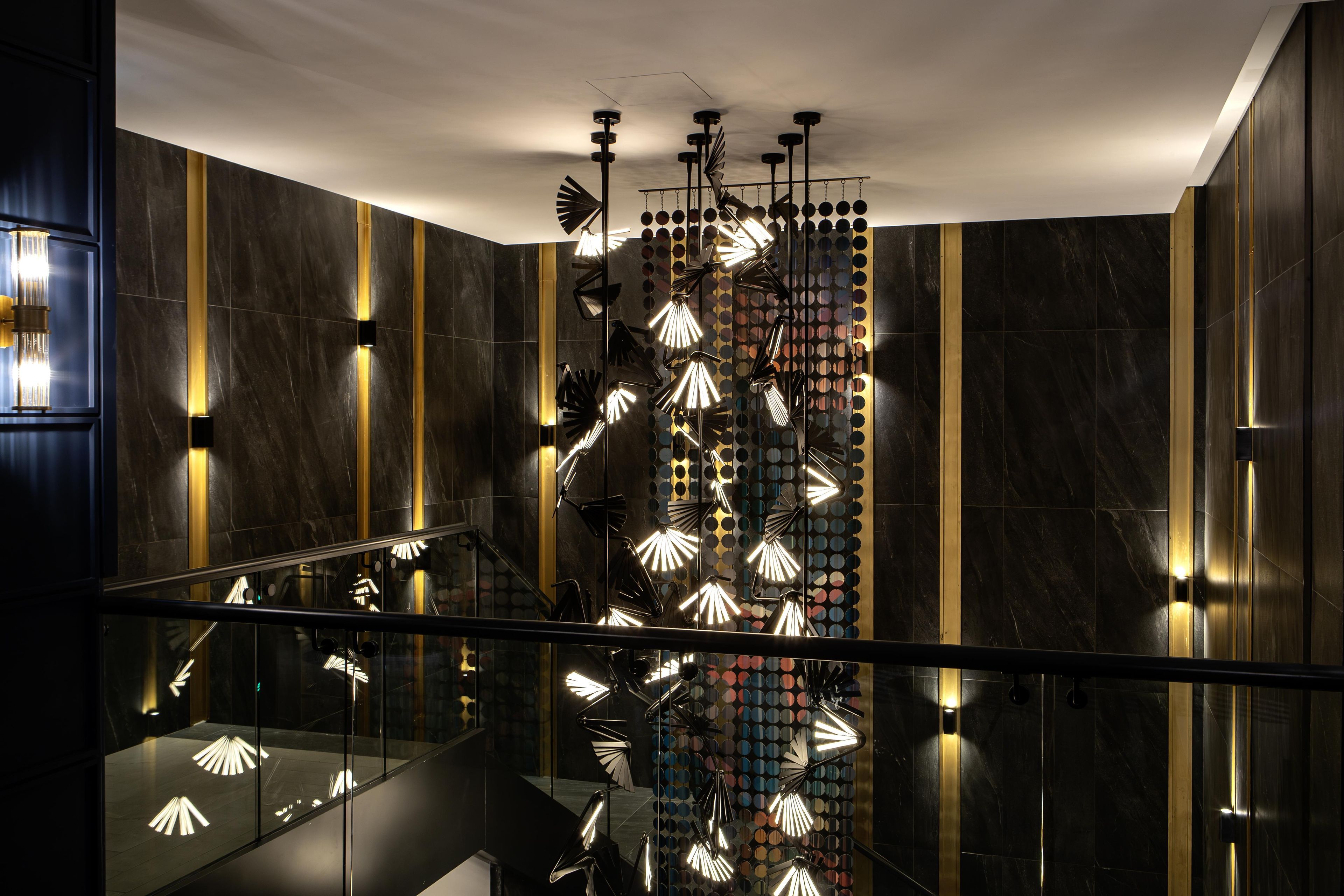 A modern interior with a staircase, reflective surfaces, and unique lighting fixtures.