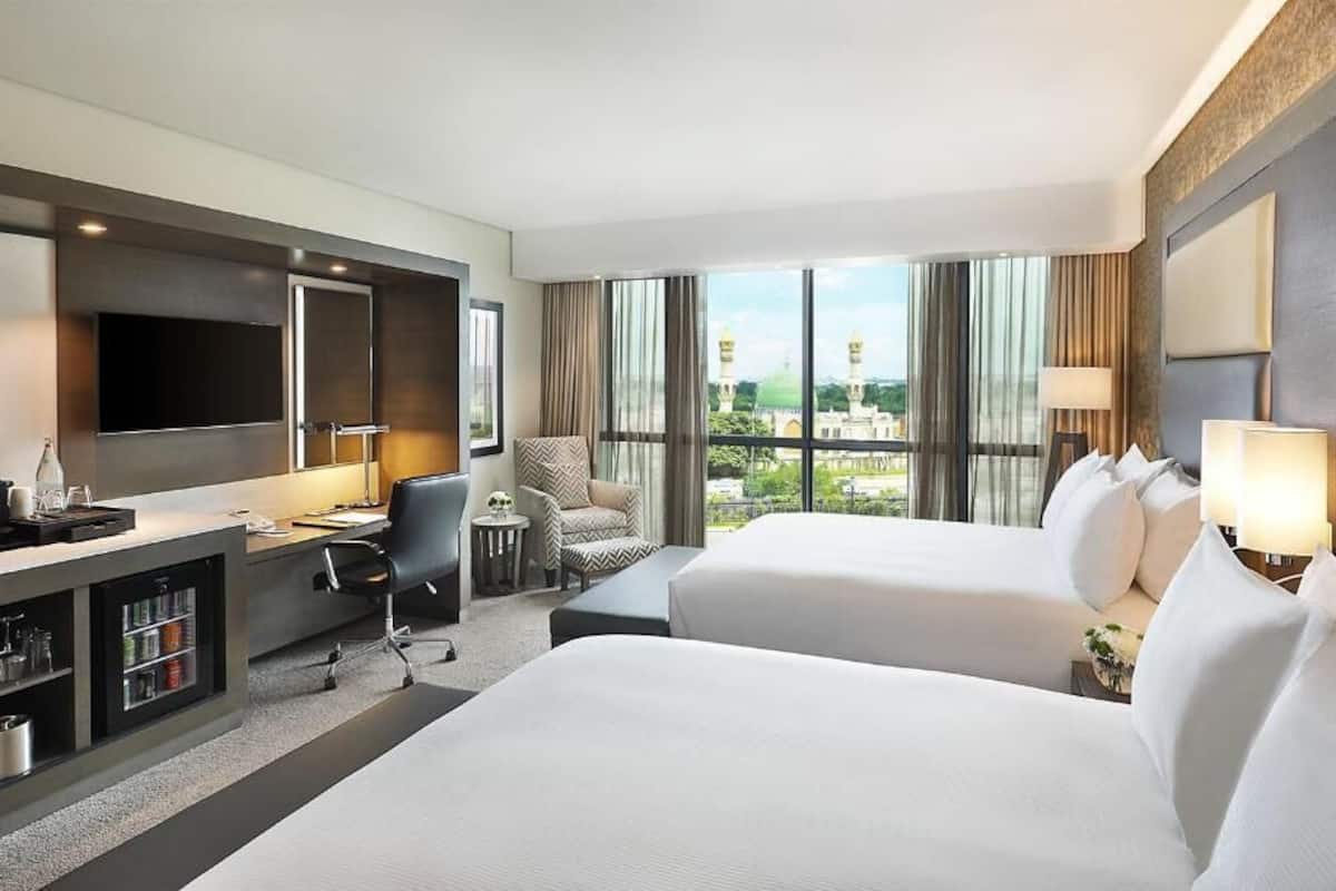 Habitación de hotel con dos camas, un escritorio, un televisor y un minibar.