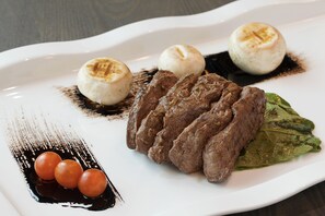 A white plate with grilled meat, three round items, and a sauce.