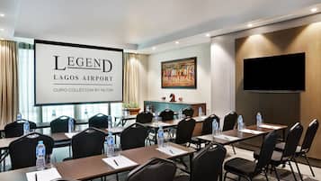 Une salle de conférence dotée d’un grand écran affichant la mention : « LEGEND LAGOS AIRPORT CURIO COLLECTION BY HILTON ».