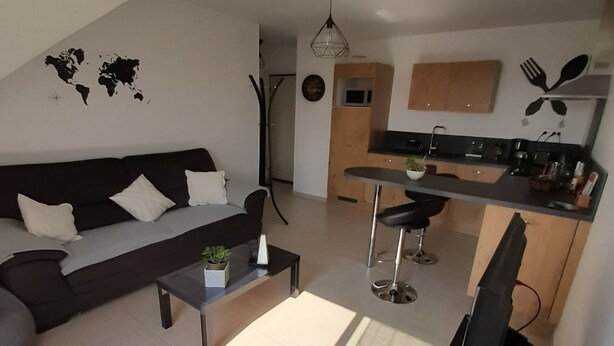 Ein zeitgemäßer Wohnbereich mit einer Couch, einem Couchtisch und einem Essbereich mit einer Bar.