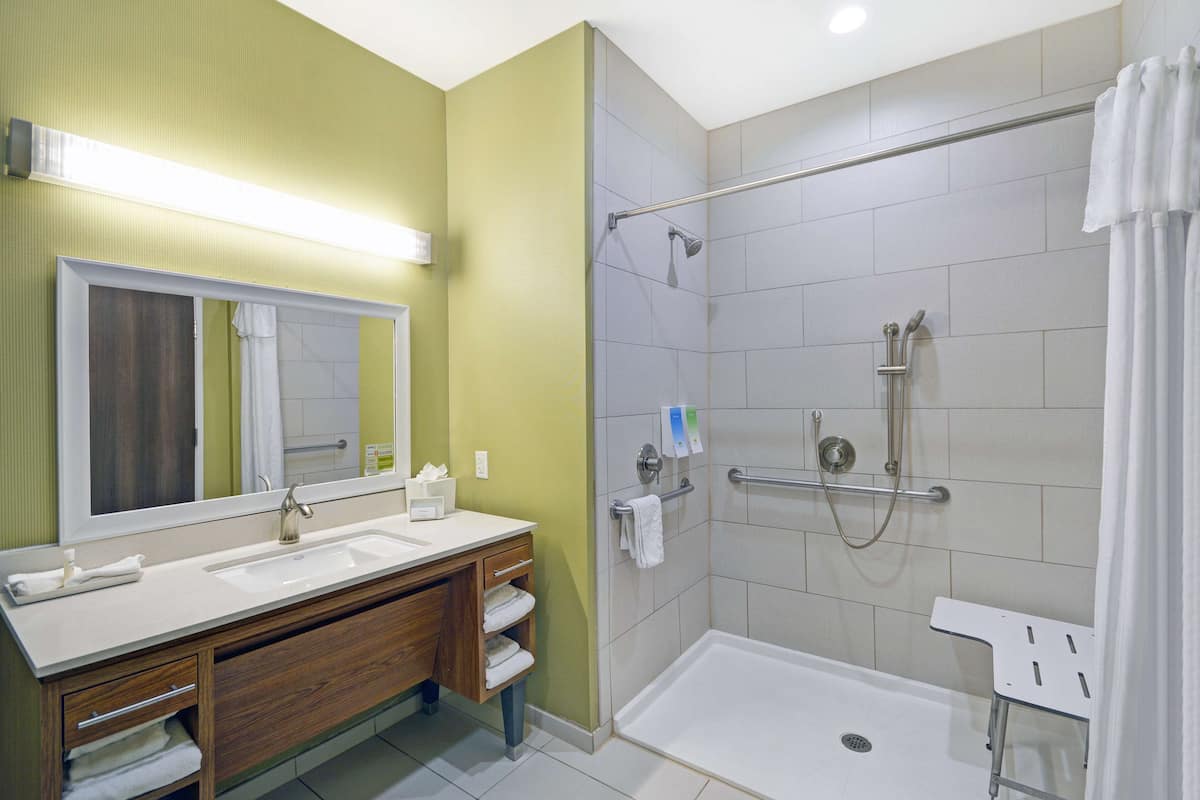 Une salle de bain dotée d’un meuble-lavabo à deux vasques, d’une douche avec une porte en verre et d’un miroir au-dessus du lavabo.