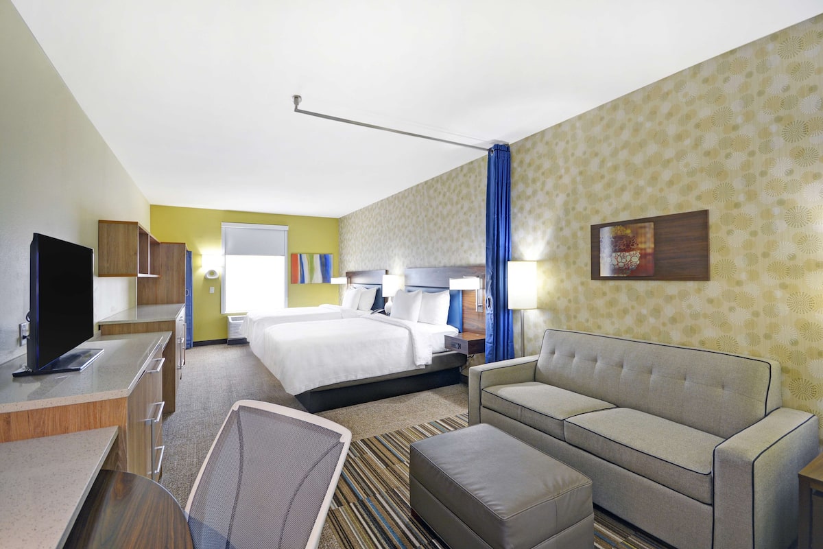 Une chambre d’hôtel avec un lit, un canapé, un bureau et une télévision.