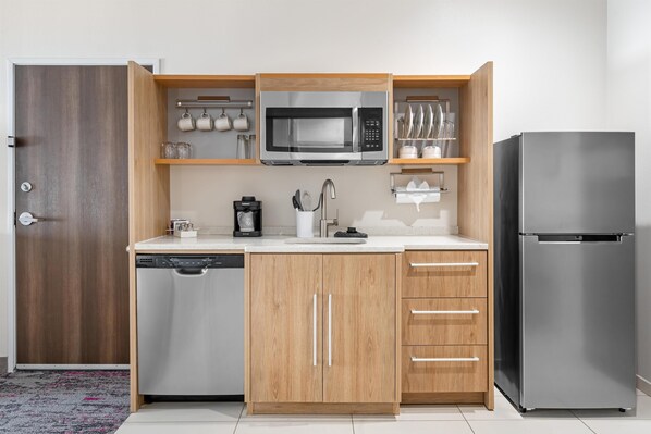 Una cocina compacta equipada con lavavajillas, microondas, refrigerador y armarios de madera.