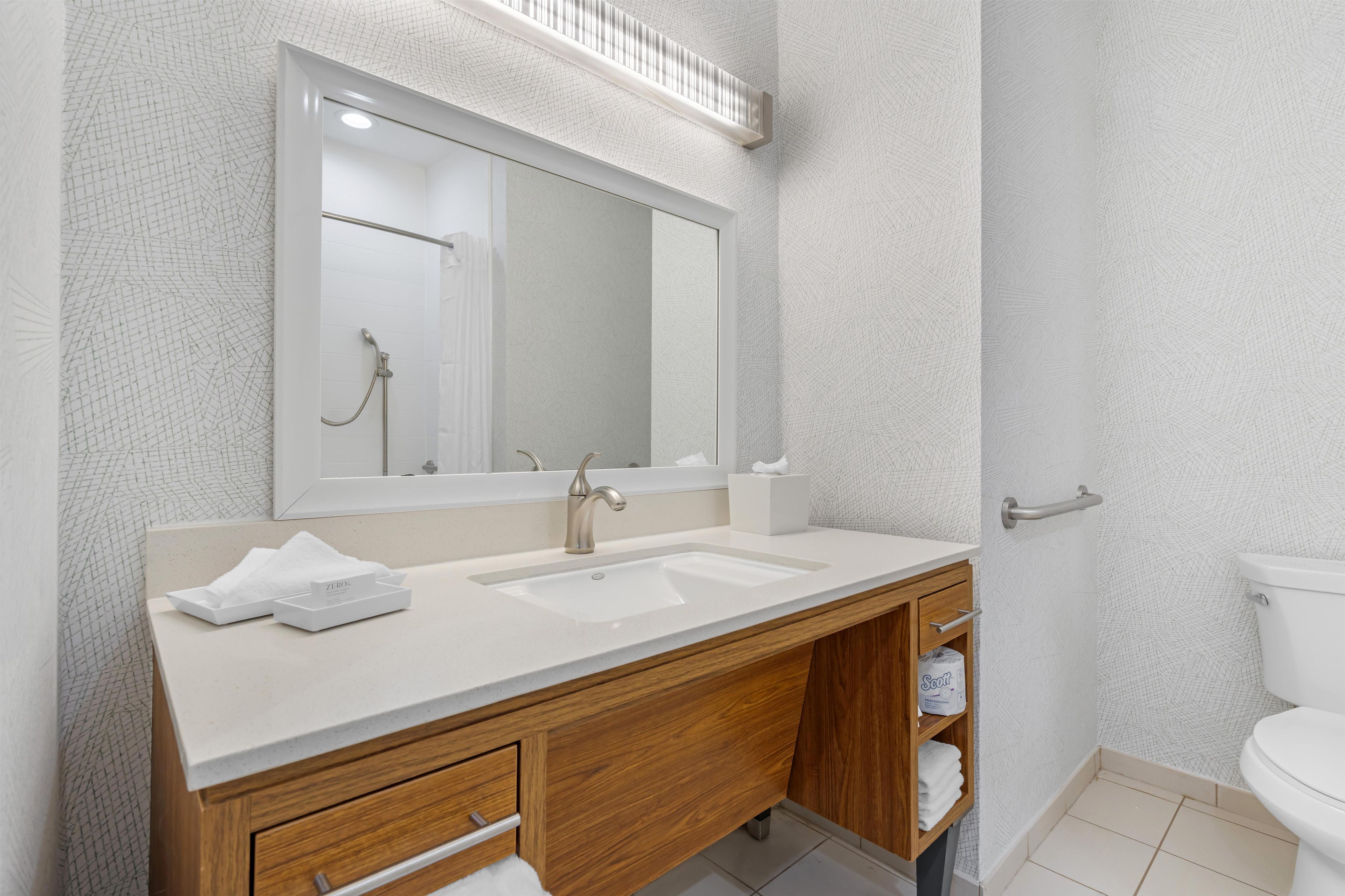Un baño moderno con lavamanos doble, tocador de madera y un espejo grande.