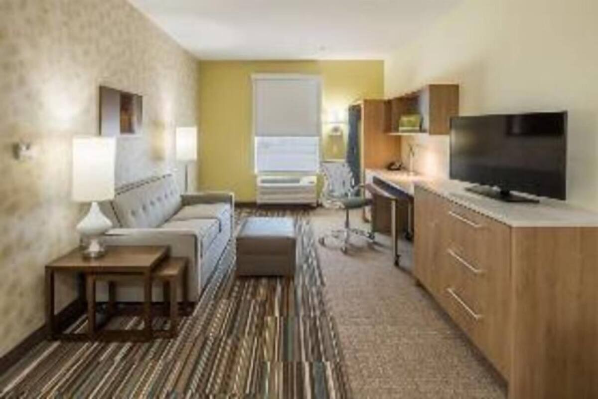 Une chambre d’hôtel avec un canapé, une télévision, un bureau et une fenêtre.