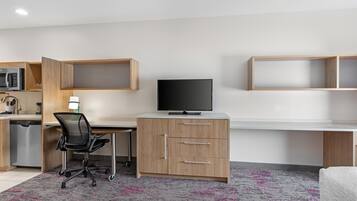 Een moderne, goed verlichte kamer met een bureau, stoel en een televisie.