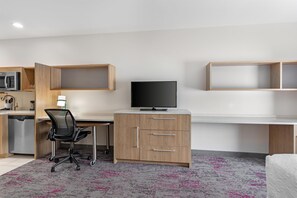 A modern, well-lit room with a desk, chair, and a television. - Home2 Suites by Hilton Dallas DeSoto (DeSoto)