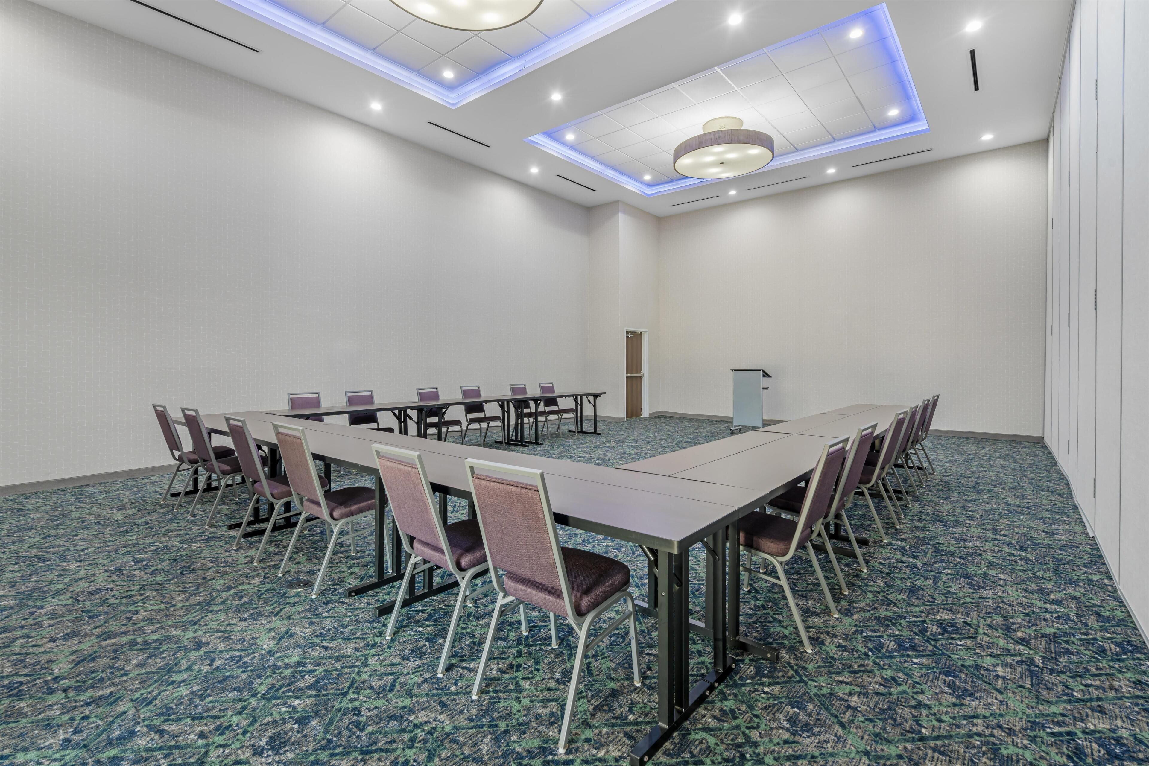A conference room with a long table and chairs, carpeted floor, and a ceiling with recessed lighting.